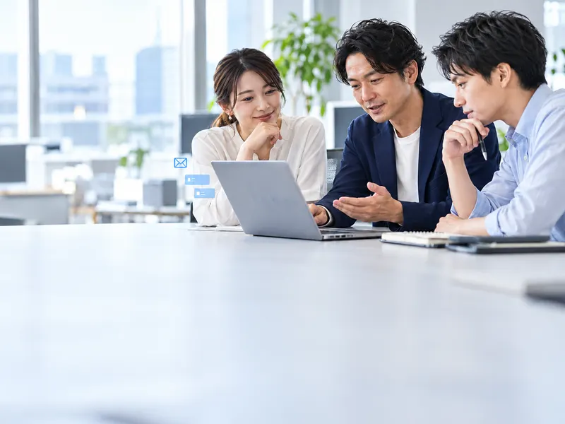 AIディレクターがチームに加わり、ノートPCを囲んで社内の担当者2人と仕事の進め方を組み直している様子